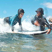El monitor de surf empuja a los niños a las olas