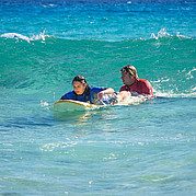 El instructor de surf empuja a los estudiantes de surf hacia la ola